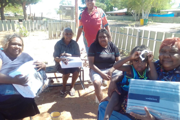 A group of smiling Indigenous women from a remote community with donations of Sheridan bedding